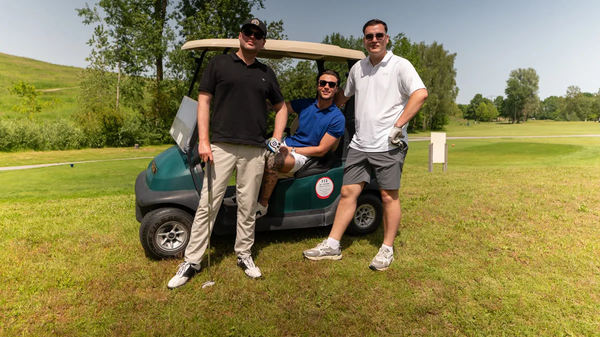 Drie deelnemers bij een golfkar